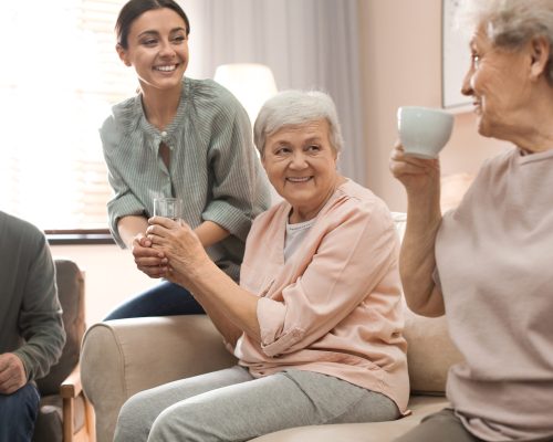 Young woman taking care of elderly people in living room